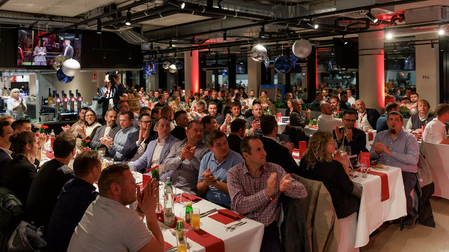 Personen sitzt in der Linz Location an mehreren Tischen und applaudieren