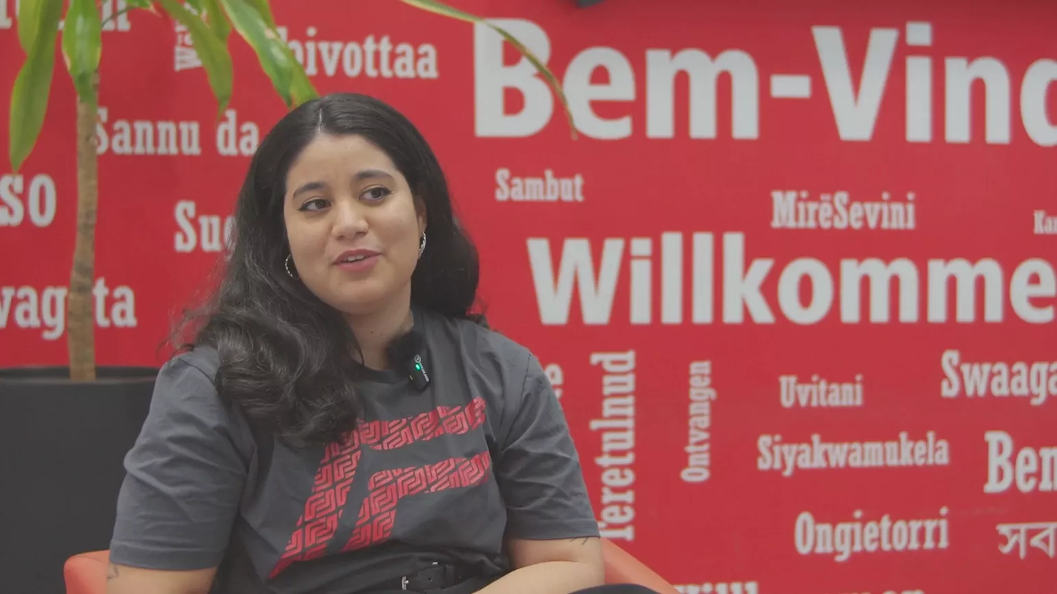 Uma jovem está sentada em uma cadeira enquanto explica informações sobre a Fronius.