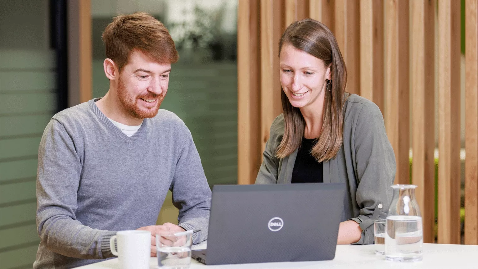 2 Mitarbeiter an einem Tisch mit Laptop