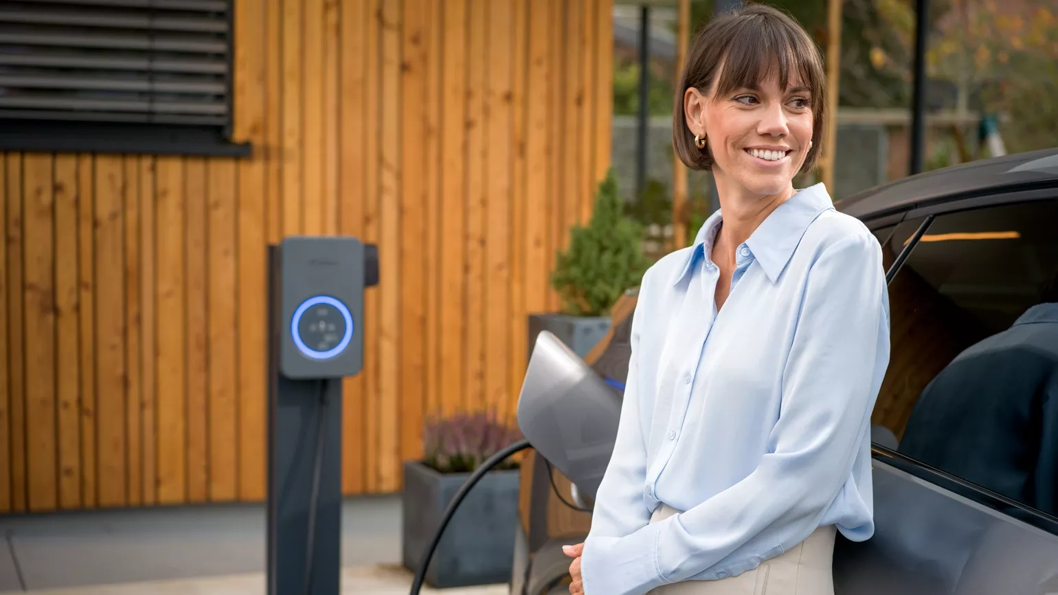 Woman next to her car while charging it with the Fronius Wattpilot Flex