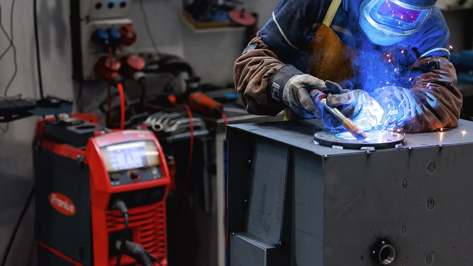 A person is welding with a Fronius welding machine in Fronius protection clothing