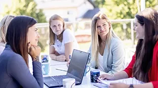 Eine Gruppe von Fronius Mitarbeiterinnen sitzt an einem Tisch im Außenbereich und bespricht ein Thema.