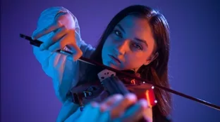 Junge Frau mit Violine in der Hand vor blauem Hintergrund
