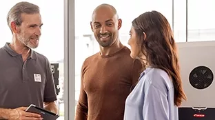Tres personas conversan frente a un inversor Fronius.