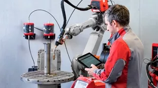 Spawacz korzystający z robota spawalniczego TPSi
