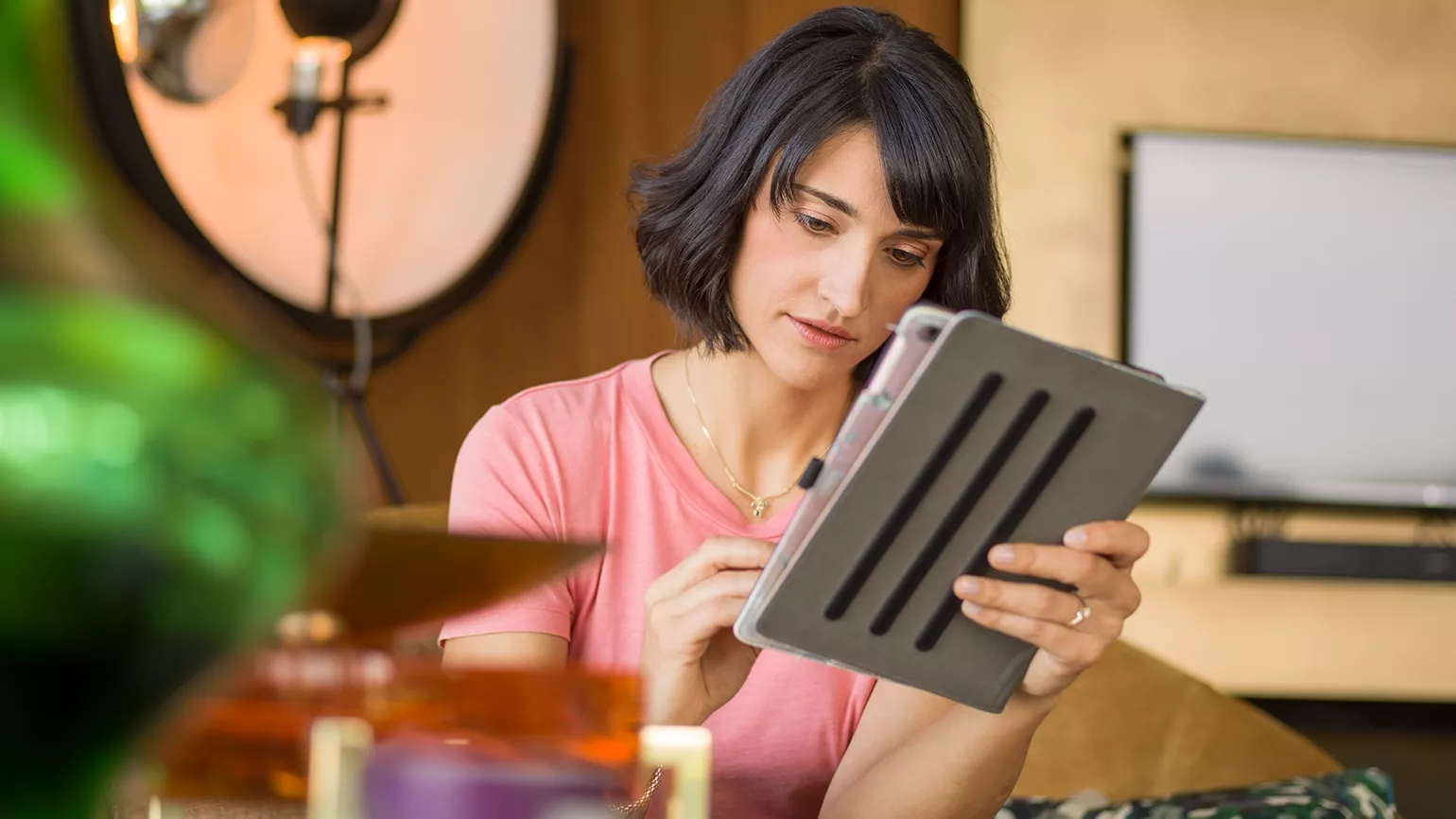 Person sitting on a sofa in a modern living room using a tablet.