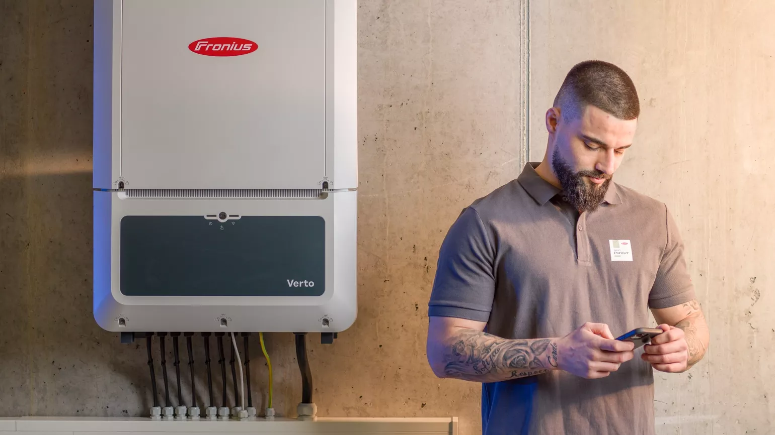 Installateur mit Smartphone neben Verto Wechselrichter