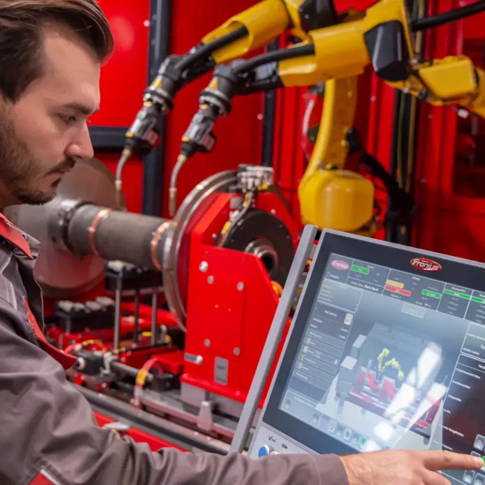 Mann steuert ein Fronius Roboterschweißsystem.