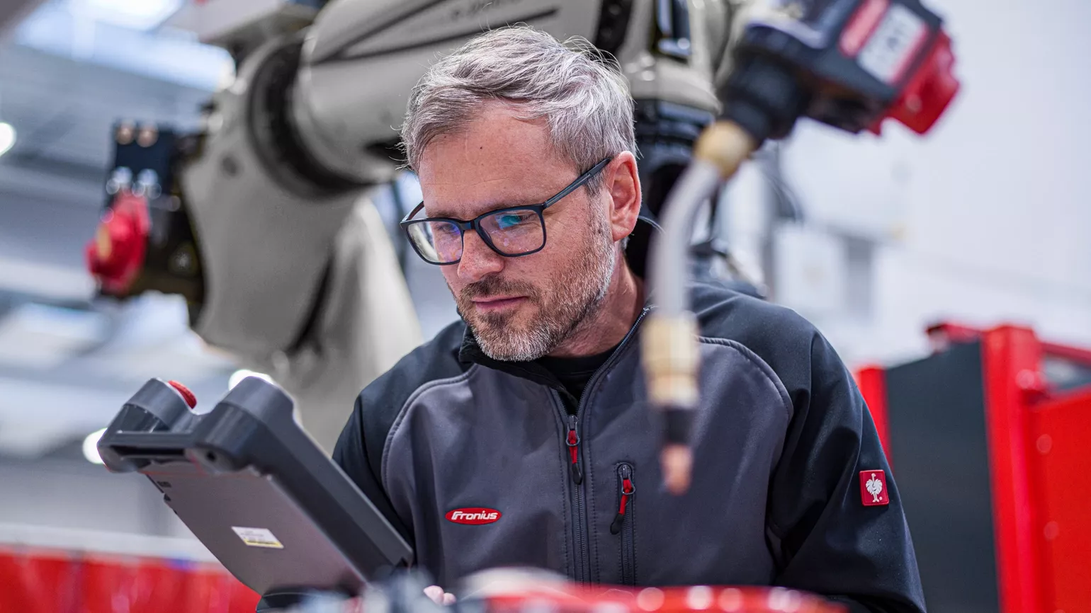 Welder making adjustments to Fronius MIG/MAG welding robot