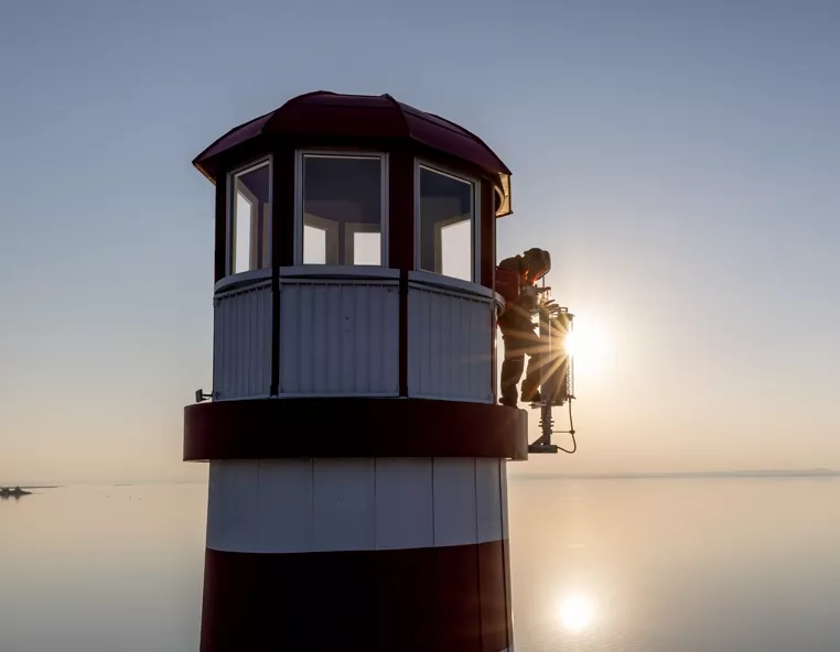 Eine Person mit Fronius Schweißgerät-Ausrüstung, im Hintergrund Wasser